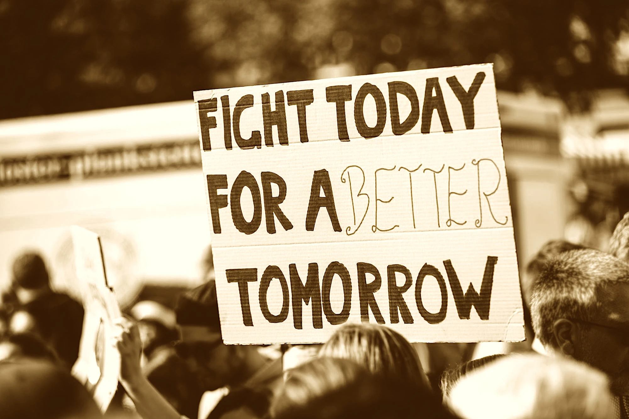 Photo of a protest with someone holding a sign saying Fight Today For a Better Tomorrow.