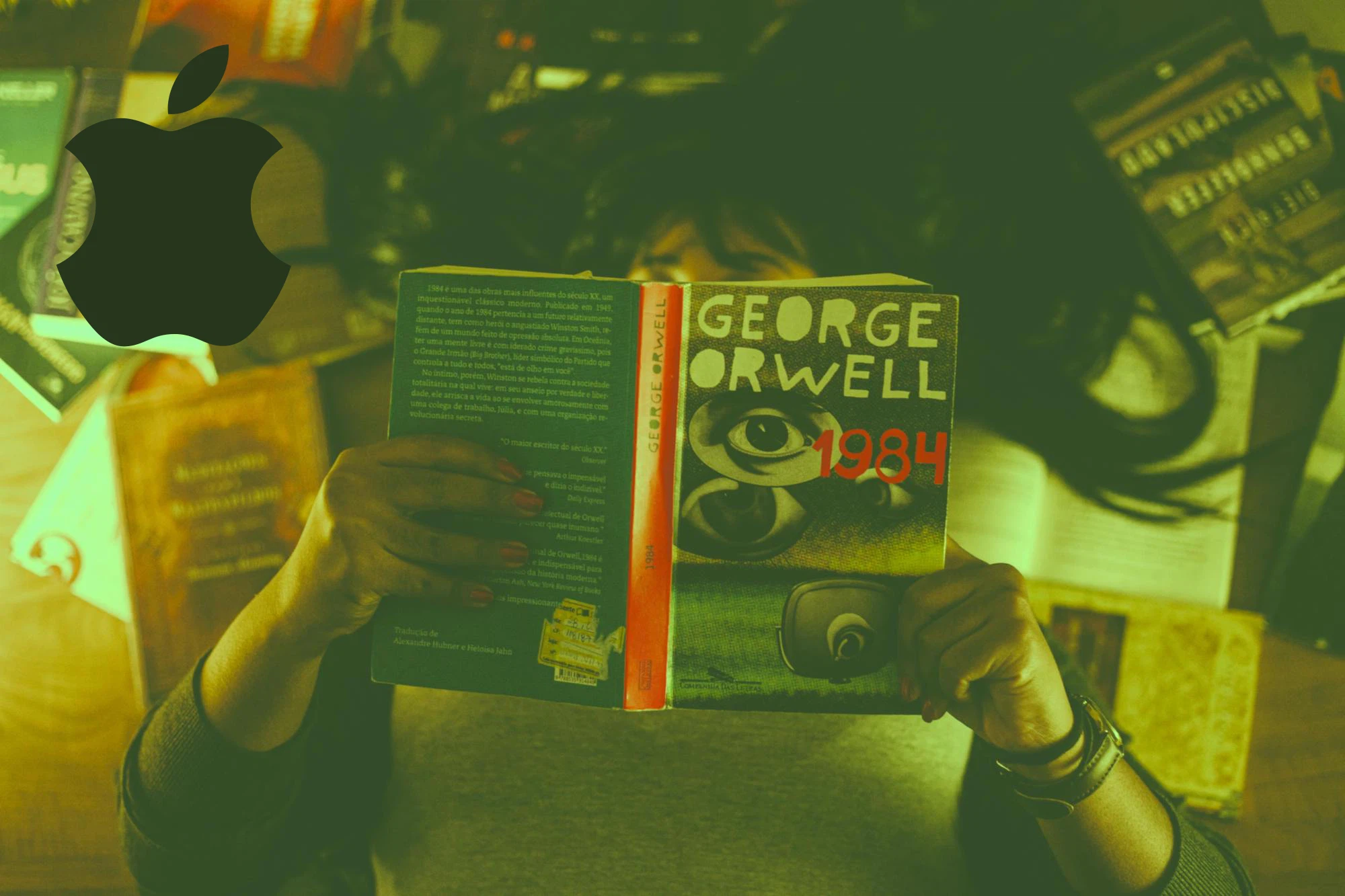 Photo of a person reading a book. The book is George Orwell's 1984. In the upper left corner is an Apple logo with two bites taken off.